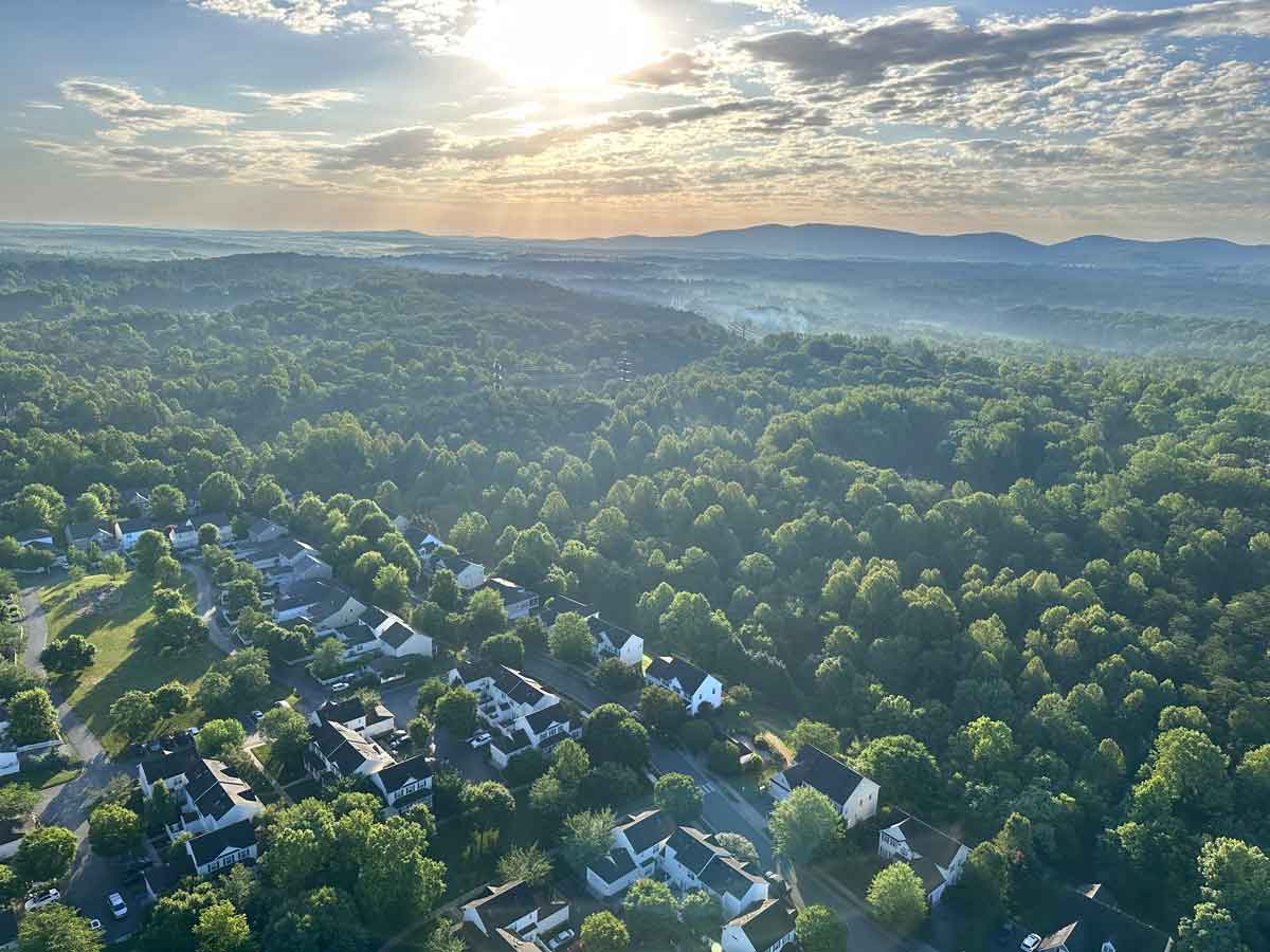 Aerial view of Crozet rooftops nestled among trees with the Blue Ridge in the distance at sunrise