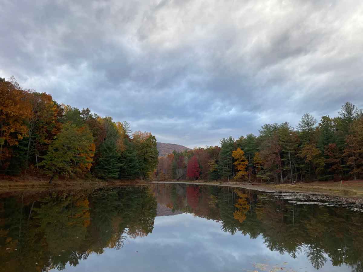 Reservoir surrounded by autumn foliage with mountains reflected in glassy water