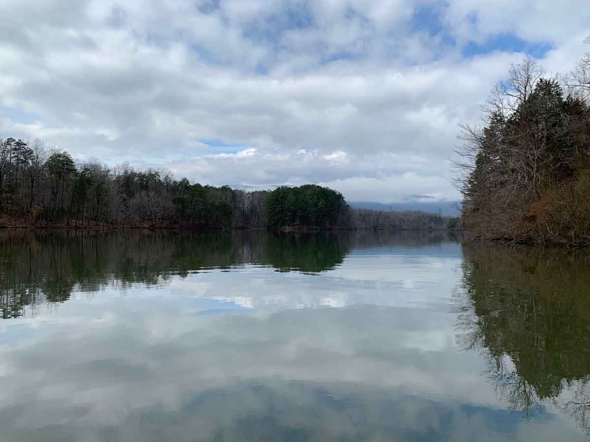 Quiet winter morning at a reservoir, bare trees and misty Blue Ridge reflected in still water